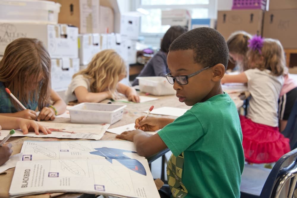 Niños realizando actividades de escritura y dibujo en el aula